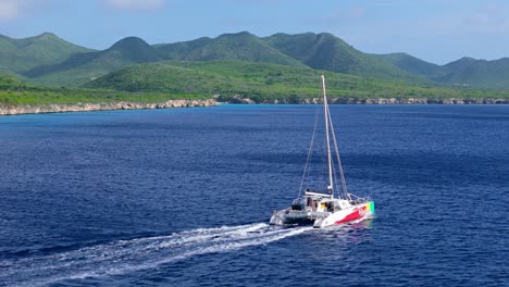 Catamaran-cruises-in-open-ocean-along-Caribbean-coastline-of-Westpunt,-Curacao
