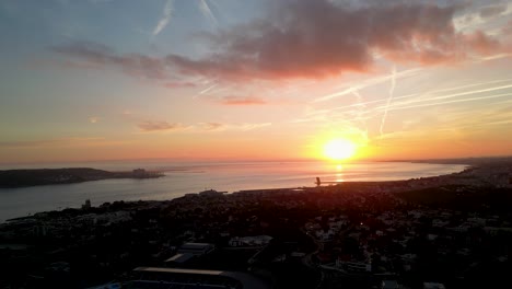 Fesselnde-Luftperspektive:-Der-Sonnenuntergang-Malt-Den-Horizont-Des-Ozeans,-Mit-Einer-Küstenstadt-Im-Vordergrund,-Und-Schafft-So-Ein-Spektakuläres-Und-Ruhiges-Bild