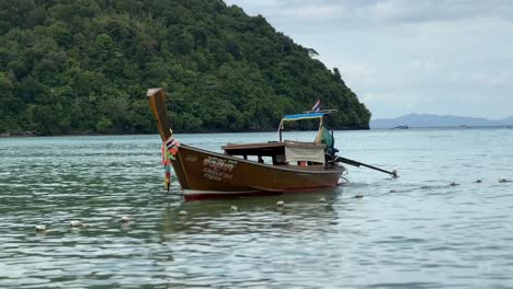 A-long-tail-boat-peacefully-anchors-near-the-shore-in-Krabi,-Thailand