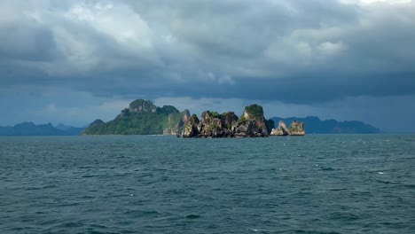 The-vessel-approaches-a-fascinating-rocky-formation-in-cloudy-Krabi,-Thailand