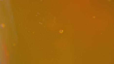 Pair-of-bubbles-adhering-to-a-surface-with-a-coppery-yellowish-background,-consistency-of-beer