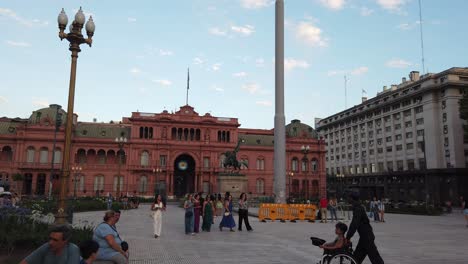 Menschen-Gehen-Am-Historischen-Platz-Plaza-De-Mayo-In-Buenos-Aires,-Argentinien,-Vorbei.-Rosafarbenes-Haus,-Regierungsgebäude-Und-Skyline
