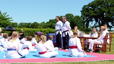 Taekwondo-Lehrer-Mit-Schwarzem-Gürtel-Sprechen-Während-Einer-Zeremonie-Im-Freien-Mit-Jungen-Taekwondo-Schülern