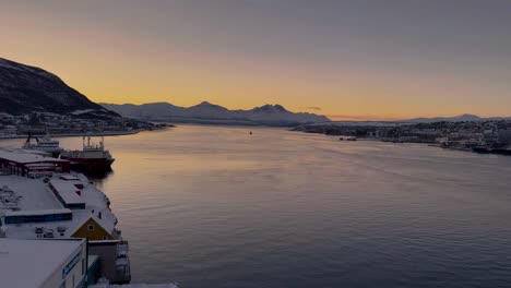 Magischer-Sonnenuntergang-In-Tromsø,-Bedeckt-Mit-Schnee-Am-Meeresufer-Mit-Bergen-Im-Hintergrund