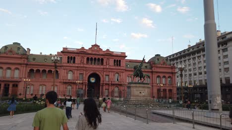 Touristen-Gehen-Auf-Der-Plaza-De-Mayo,-Dem-Berühmten-Argentinischen-Platz,-Mit-Menschen-Und-Dem-Präsidentengebäude-Des-Rosafarbenen-Hauses-Spazieren