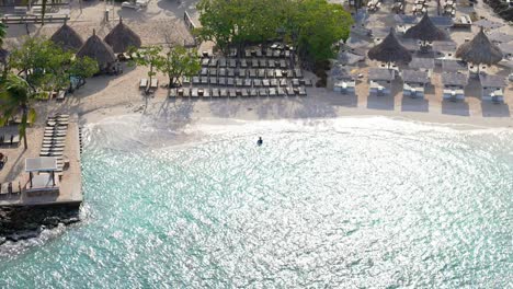 Tourists-swim-in-stunning-Caribbean-waters-of-Zanzibar-beach-Jan-Thiel-Curacao,-aerial-overview
