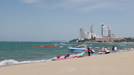 Local-and-foreign-tourists-are-strolling,-taking-pictures-and-jet-skiing-at-the-beachfront-of-Pattaya-Beach,-in-Chonburi-province-in-Thailand
