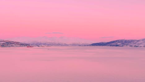 Wide-view-of-the-sea-in-Tromso-Norway,-with-pink-hues-and-snow-covered-mountains-in-the-distance
