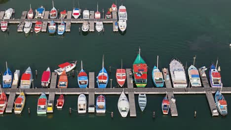 Drone-bird's-eye-view-pan-across-colorful-boats-docked-at-fishing-harbor-pier-in-Caribbean