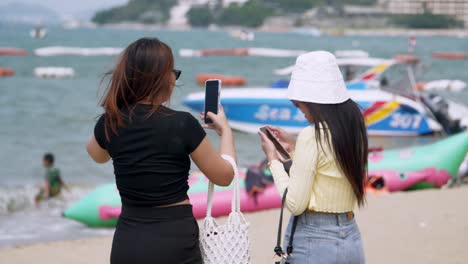 Tourists-taking-photos-and-videos-while-checking-their-social-media-statuses-at-the-beachfront-of-Patttaya,-in-Chonburi-province-in-Thailand