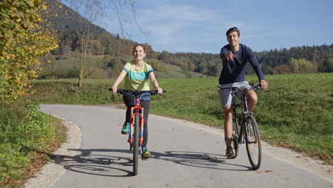 Pareja-Disfrutando-Del-Ciclismo-En-El-Campo-Durante-El-Viaje-De-Fin-De-Semana-De-Otoño,-Vista-Frontal