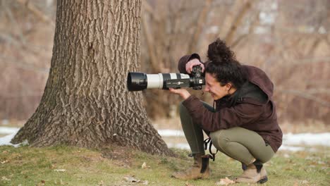 Woman-wildlife-photographer-is-filming-next-to-an-oak-tree-in-a-city-park