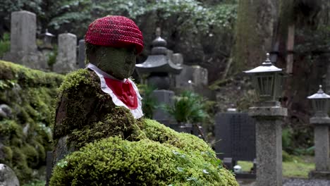Primer-Plano-Panorámico-De-Una-Estatua-De-Piedra-De-Jizo-En-El-Cementerio-Forestal,-Japón