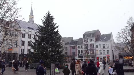 Menschen-Gehen-Auf-Dem-Marktplatz-Der-Stadt-Spazieren,-Während-Frische-Schneeflocken-Vom-Himmel-Fallen