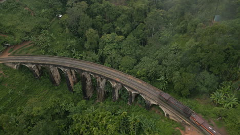High-Aerial-Drone-Shot-of-Night-Diesel-Train-Crossing-9-Arches-Bridge-on-Misty-Morning-in-Ella-Sri-Lanka
