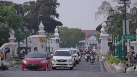 Fahrzeuge,-Die-Auf-Der-Berühmten-Straße-Von-Yogyakarta-Vorbeifahren,-Mit-Blick-Auf-Das-Weiße-Tor-Und-Das-Palastgebäude-Im-Hintergrund---Indonesien