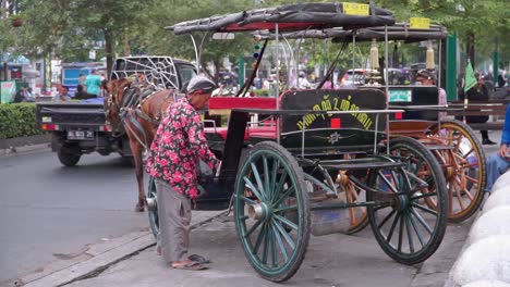 A-male-horse-driver-wearing-batik-clothes-was-standing-next-to-the-carriage