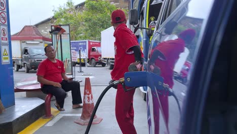 The-refueling-officer-is-inserted-the-gas-pump-hose-nozzle-on-the-car's-tank