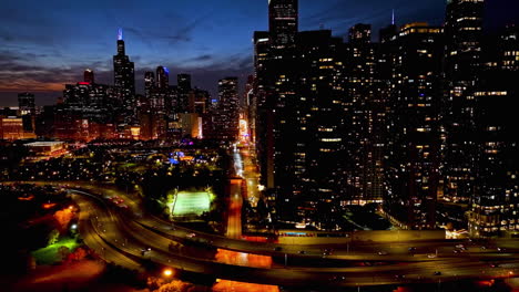 Drone-shot-of-traffic-on-the-Lake-shore-drive,-in-front-of-parks-of-Chicago