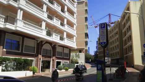 Monaco-Center,-a-beautiful-building-on-the-street,-with-a-prominent-construction-crane-in-the-background