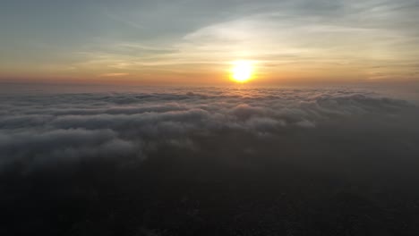 Aerial-drone-shot-of-beautiful-sun-setting-through-dark-clouds-over-umerkot-city,-Tharparkar,-Pakistan-during-evening-time