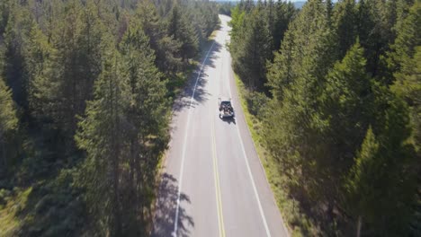 A-4K-drone-shot-of-a-truck-driving-on-a-remote-road-surrounded-by-forest