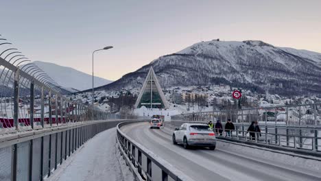 Tráfico-Y-Autopistas-En-Carreteras-Cubiertas-De-Nieve-En-Tromso,-Noruega,-Con-Montañas-En-La-Distancia