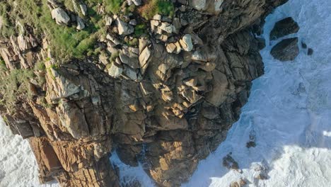 Foamy-Sea-Waves-Crashing-On-Rocky-Cliff-In-Carballo,-A-Coruña,-Spain---aerial-top-down