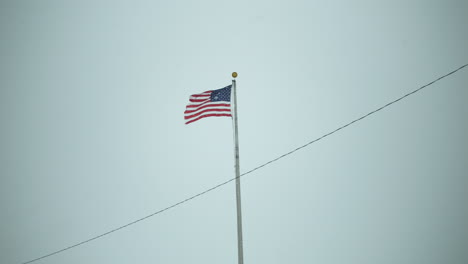 Bandera-Estadounidense-Ondeando-En-El-Viento-Con-Copos-De-Nieve-Cayendo-En-Cámara-Lenta-Tormenta-De-Nieve-Invernal