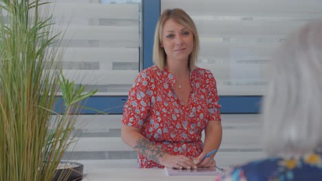 Una-Mujer-Sonriente-Con-Un-Vestido-Floral-Está-Hablando-Con-Una-Persona-Mayor