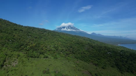 Wolken-Bedecken-Den-Gipfel-Des-Vulkans-Mount-Agung-Auf-Bali,-Indonesien,-Mit-üppigen-Grünen-Feldern-Im-Vordergrund,-Luftaufnahme