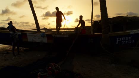 Silueta-De-Un-Hombre-Negro-Al-Atardecer-Trabajando-En-Un-Barco-De-Pescadores-En-Una-Playa-Tropical