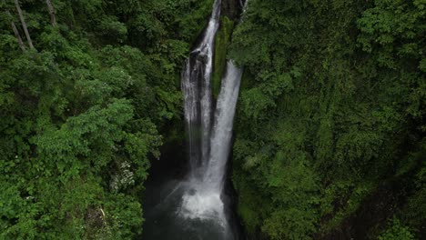 Looking-down-at-the-powerful-Aling-Aling-waterfall-in-Bali,-Indonesia-on-an-overcast-afternoon,-aerial