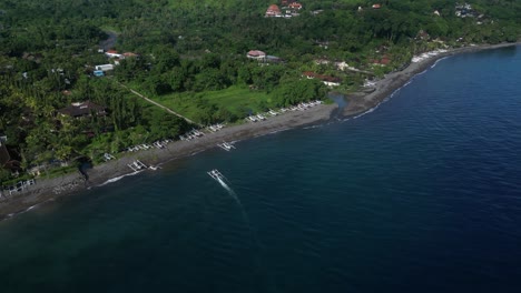The-beautiful-sunny-coastline-of-Amed,-Bali,-Indonesia-with-a-boat-coming-in-to-dock
