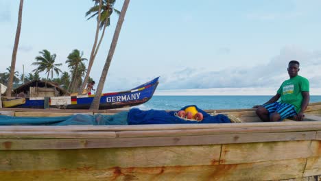 In-Afrika-Heimischer-Schwarzer-Fischer-Bereitet-Netz-In-Holzboot-Am-Tropischen-Strand-Vor