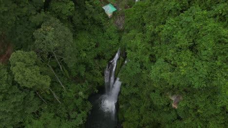 A-scenic-waterfall-surrounded-by-trees-and-huts-in-Bali,-Indonesia