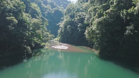 Tropical-river-flows-through-green-forest-jungle,-aerial-dolly-establisher