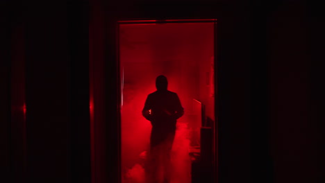 Zeitlupenzoom-Einer-Bösen,-Schattigen-Figur,-Die-Ein-Messer-Im-Leuchtend-Roten-Nebel-Hält