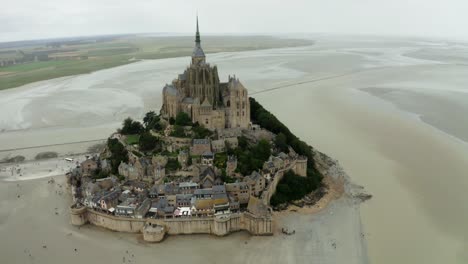 Mont-Saint-Michel-Drohnenkamera-Im-Rückblick-Kommen-Viele-Touristen-Zurück,-Nachdem-Sie-Das-Schloss-Gesehen-Haben