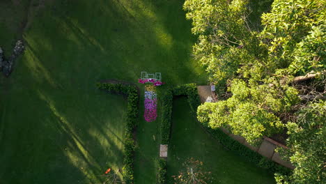 Drone-Flyover-Green-Garden-Wedding-Arbour-Setup-With-Rose-Petals,-4K