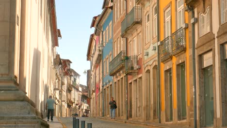 Menschen,-Die-Auf-Der-Von-Farbenfrohen-Gebäuden-Gesäumten-Straße-In-Der-Historischen-Stadt-Braga-In-Portugal-Spazieren