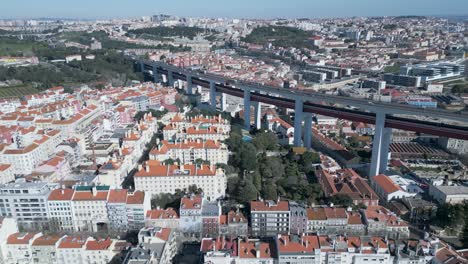 Aerial-of-houses-with-orange-roof-in-Lisbon,-Portugal-and-suspended-motorway,-pan-right