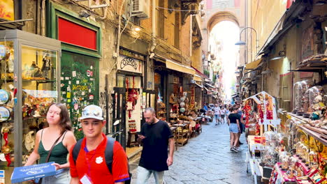 Busy-narrow-street-with-shops-and-pedestrians,-vibrant-city-life-Via-San-Gregorio-Armeno---Naples,-Italy