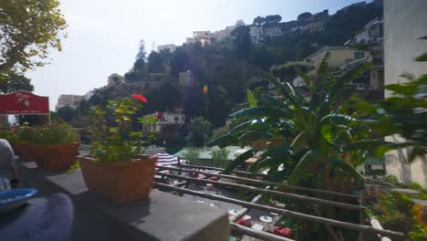 Amalfi-Positano-Italy-Immersive-Travel-Tourism-Mediterranean-Sea-Coast-Water-Europe,-Walking,-4K-|-Moving-Past-Traveler-Couple-on-Motorcycle-Exploring-Roads-Below-Famous-Mountainside-Cliffs,-Shaky