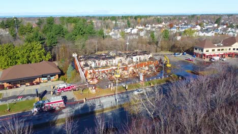 Drohnenaufnahme-Eines-Schwer-Verbrannten-Garagengebäudes,-Das-Von-Der-örtlichen-Feuerwehr-Mit-Schwerem-Gerät-Gereinigt-Wird