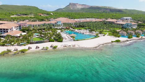 Aerial-parallax-around-Caribbean-beach-front-resort-and-stunning-infinity-pool-looking-onto-crystal-clear-reef