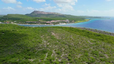 Panoramic-aerial-dolly-over-dry-Caribbean-landscape-to-Sandals-Beach-Resort-in-the-distance