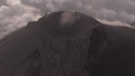 Aerial-view-tilting-toward-an-volcanic-caldera,-smoking-high-on-top-of-highlands