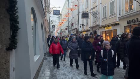 People-walking-on-winter-street-day-with-Christmas-lights,-European-holidays