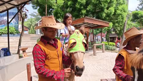 Los-Niños-Visitantes-Pueden-Montar-A-Caballo-Guiados-Por-El-Personal-En-Un-Parque-Infantil-En-El-Campo,-Semarang,-Java-Central